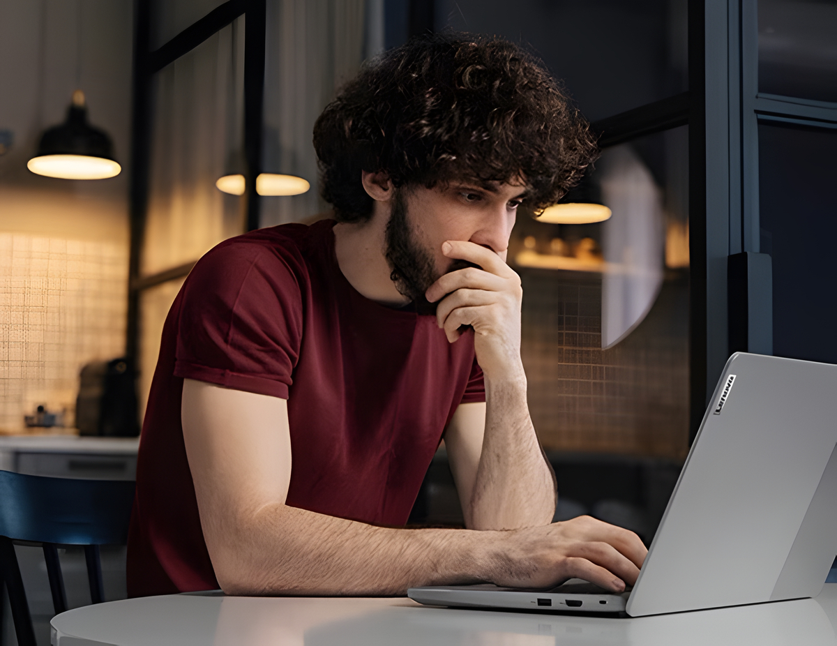 A bearded person looks thoughtful as they look at the display of the IdeaPad Slim 3i Chromebook Gen 8 14 Intel 